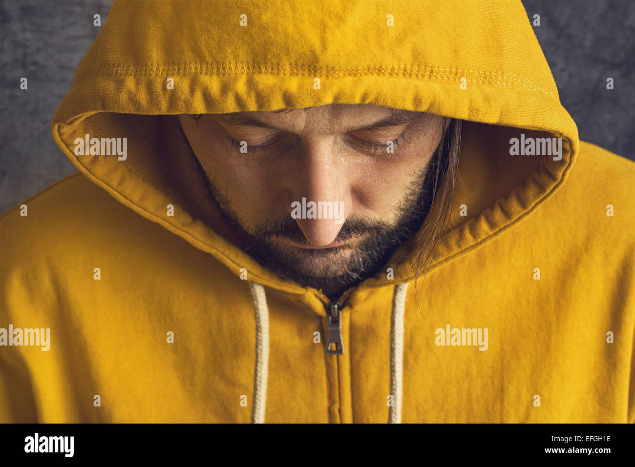 Adult Bearded Man Wearing Yellow Hooded Jacket, Eyes Closed. Stock Photo