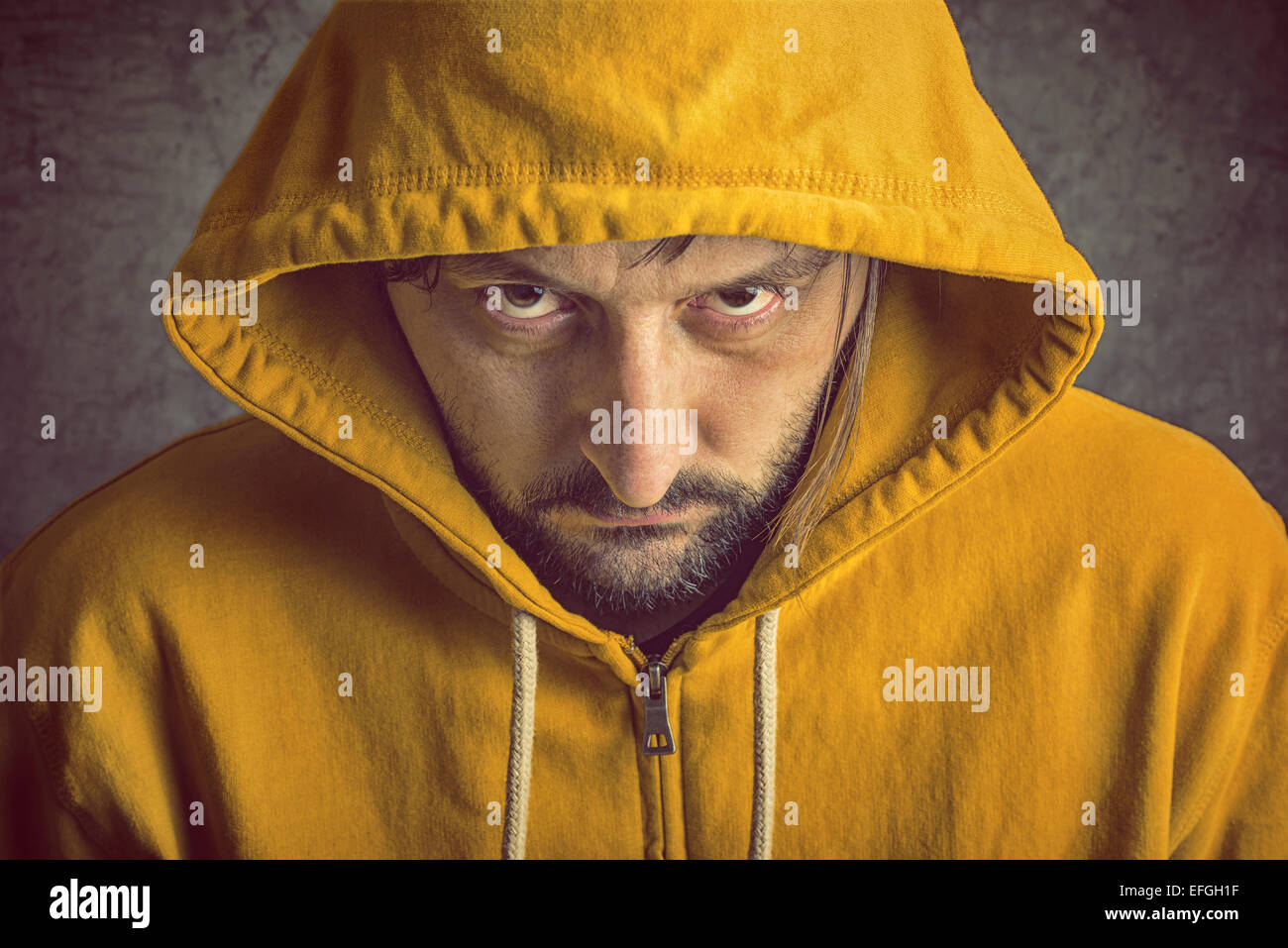 Adult Bearded Man Wearing Yellow Hooded Jacket, Looking At Camera Stock Photo