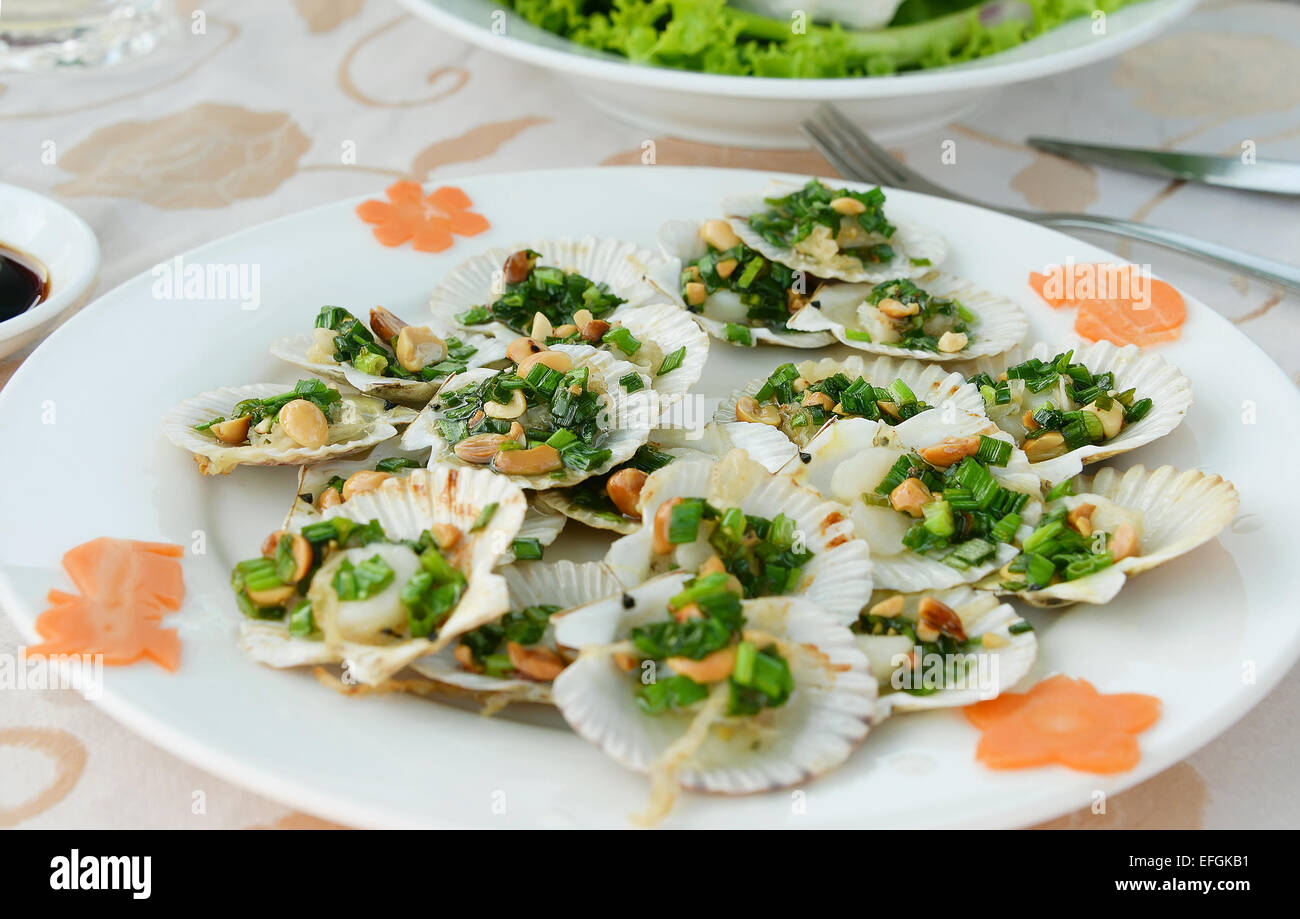 Fried scallops in shell with onion and peanuts Stock Photo