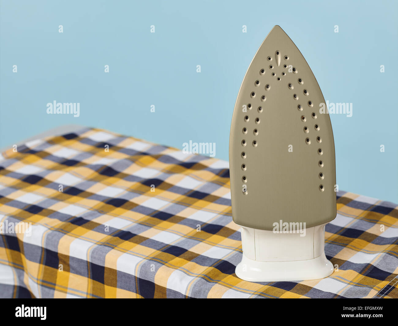 Close up, a iron and checkered shirt on the ironing board, light blue