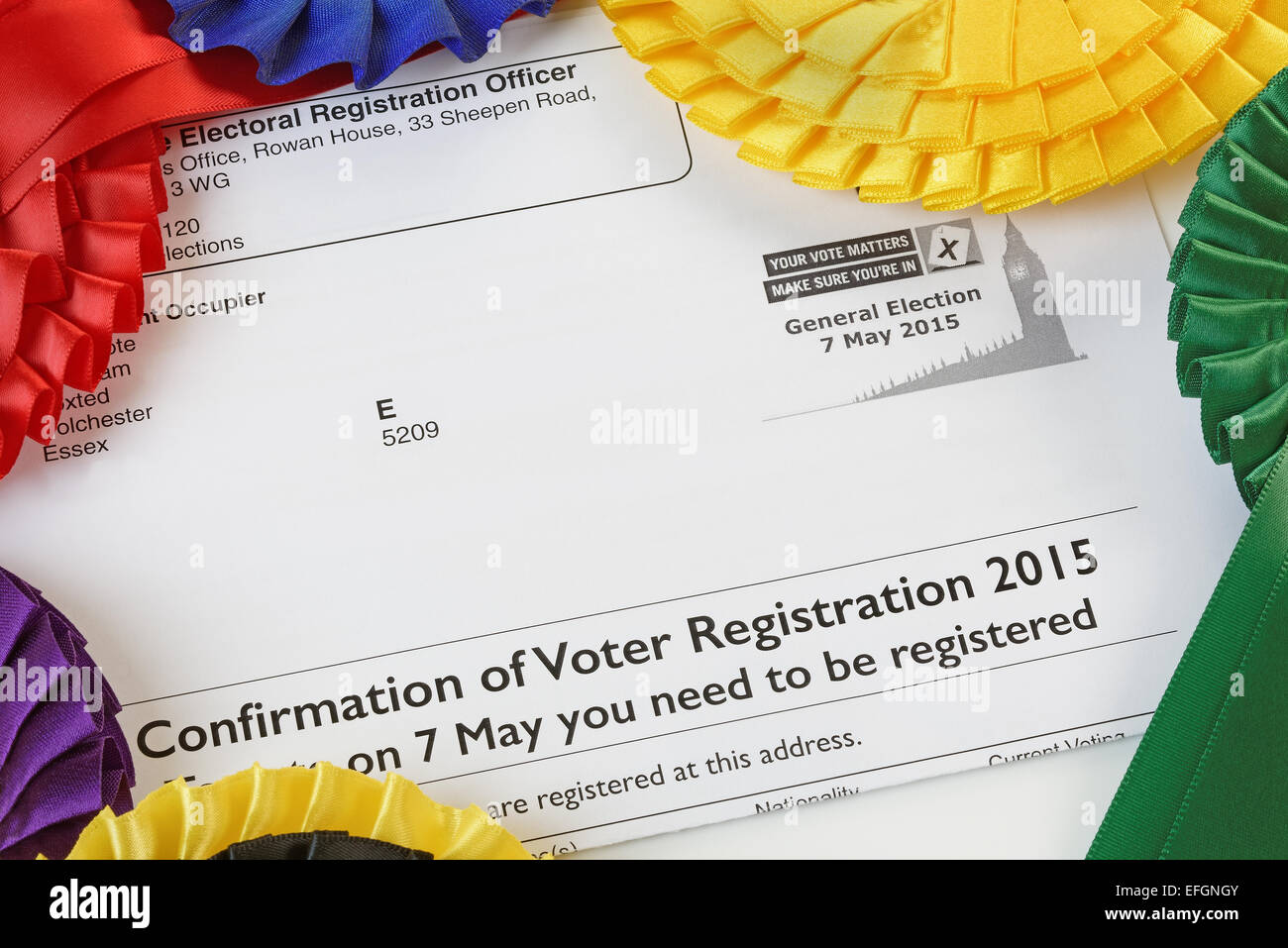 Close up of a Voter Registration Confirmation Letter for the 2015 General Election, surrounded by electoral party rosettes. Stock Photo