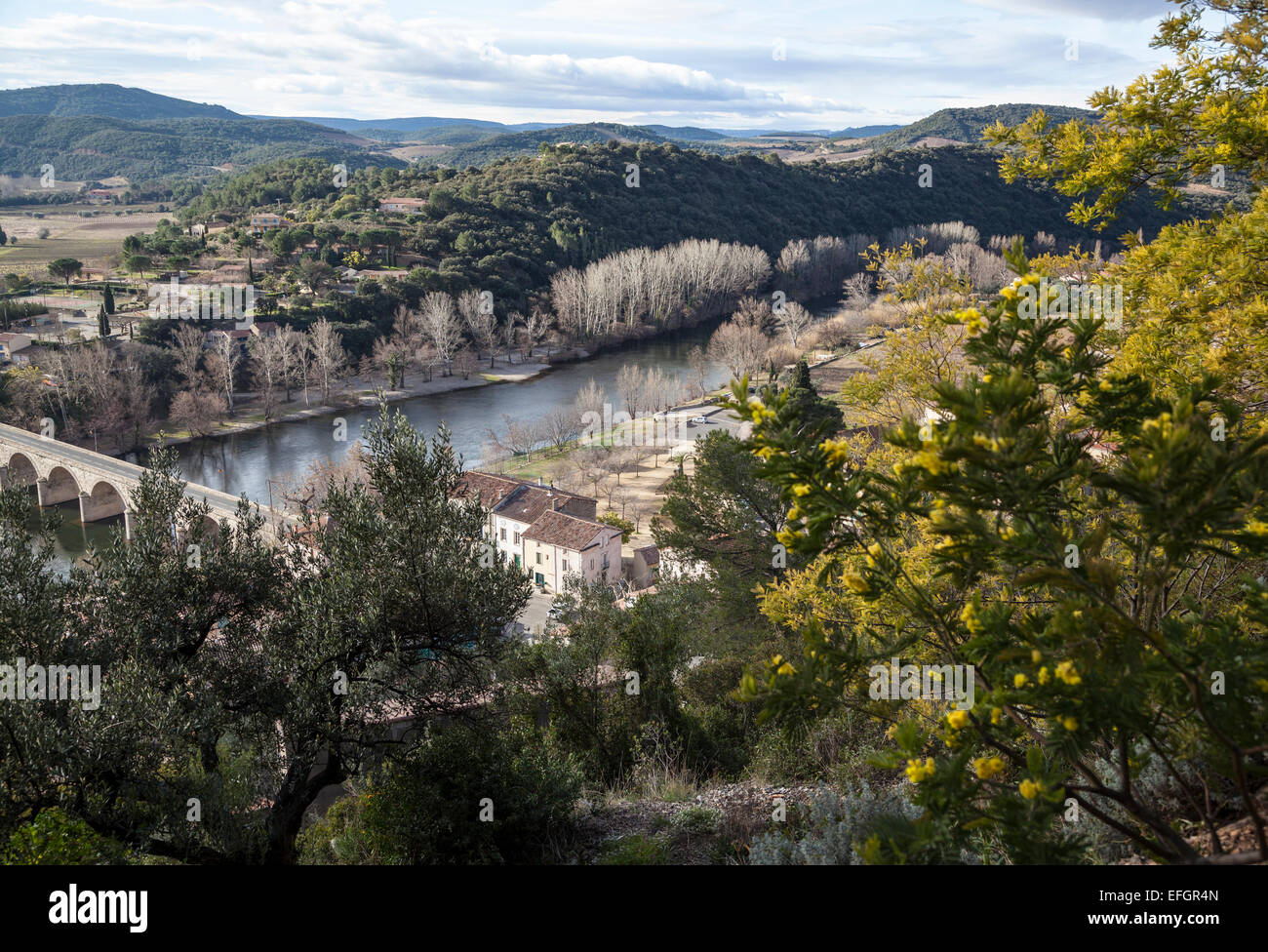 View of Roquebrun a village in the Hérault region of France on the river Orb with valley and hills in the background Stock Photo