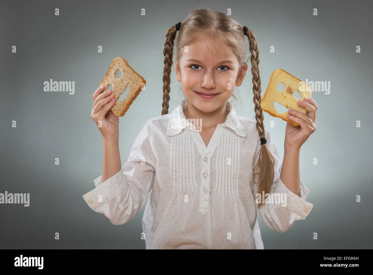 Beautiful little girl with a happy bread in one hand and the other hand