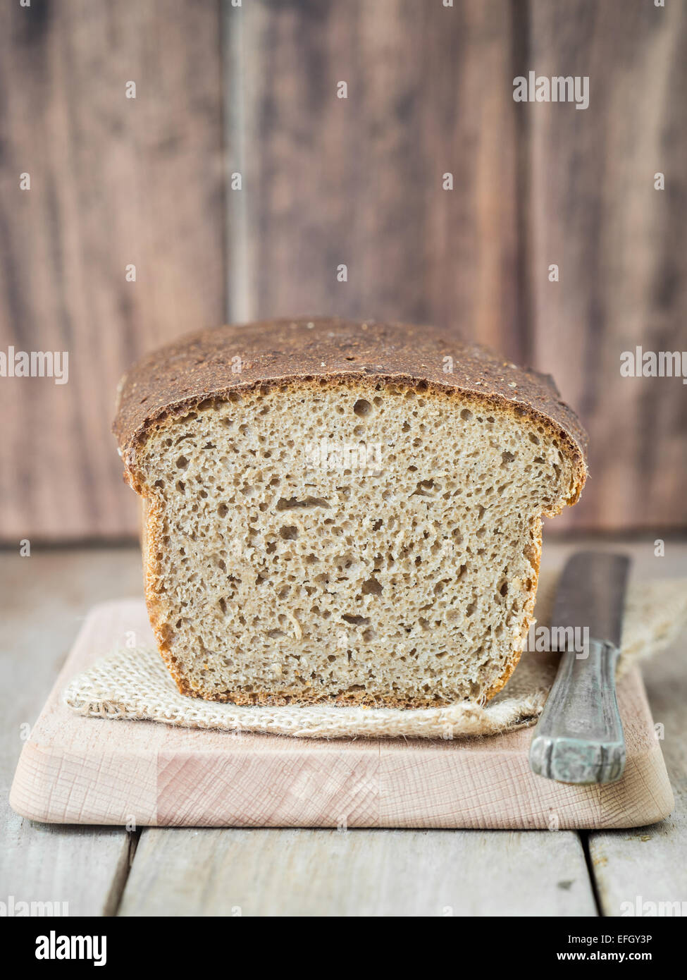 Homemade whole grain mixed rye-wheat sourdough bread on a cutting board. Stock Photo