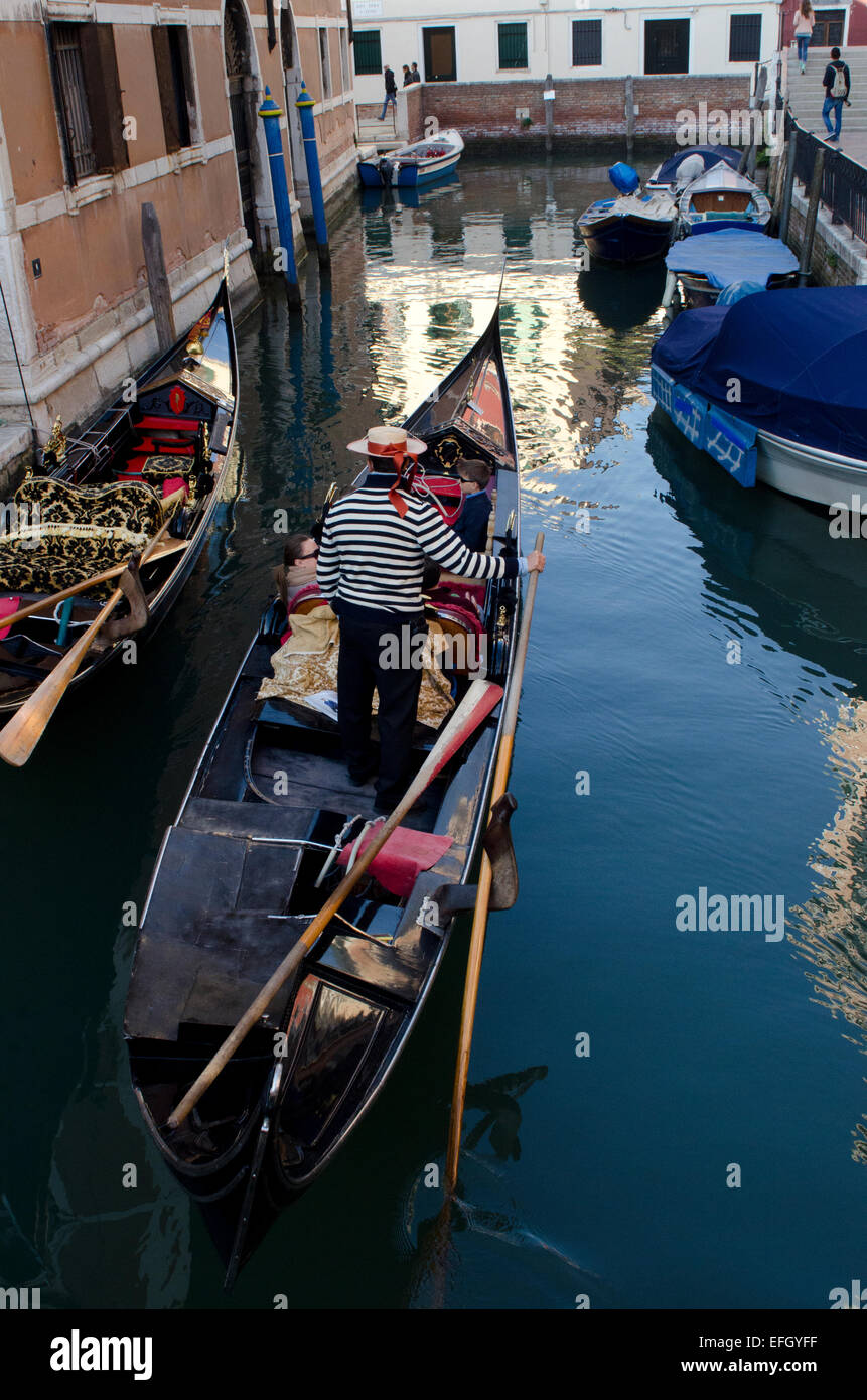 Gondolier on gondola with going past an old building in Venice, Italy Stock Photo