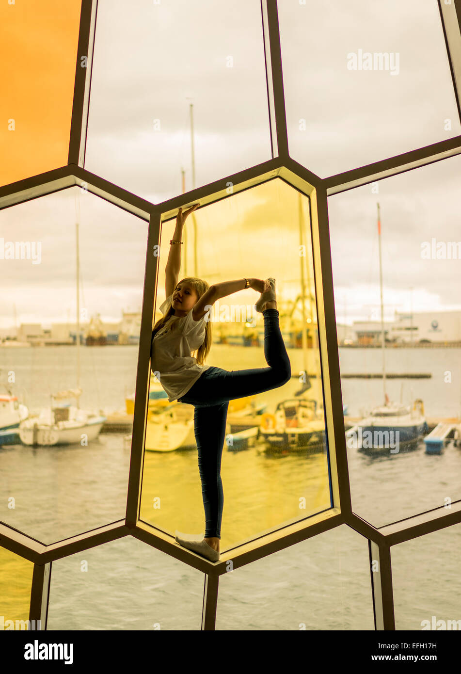 Young girl stretching in the window at Harpa Concert and Convention Center, Annual Children's Festival, Reykjavik, Iceland Stock Photo