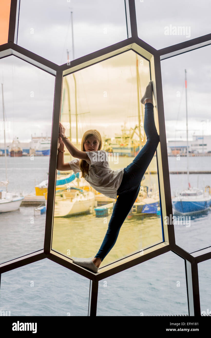 Young girl stretching in the window at Harpa Concert and Convention Center, Annual Children's Festival, Reykjavik, Iceland Stock Photo