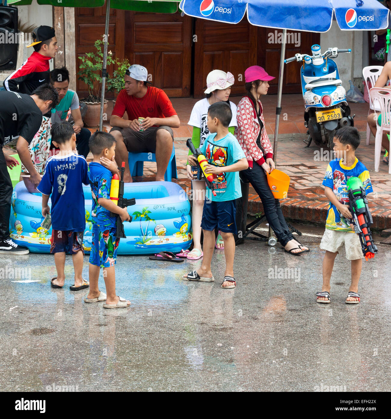 Little boys enjoy splashing people with water gun during celebration of Lao New Year and Water Festival in Luang Prabang. Stock Photo