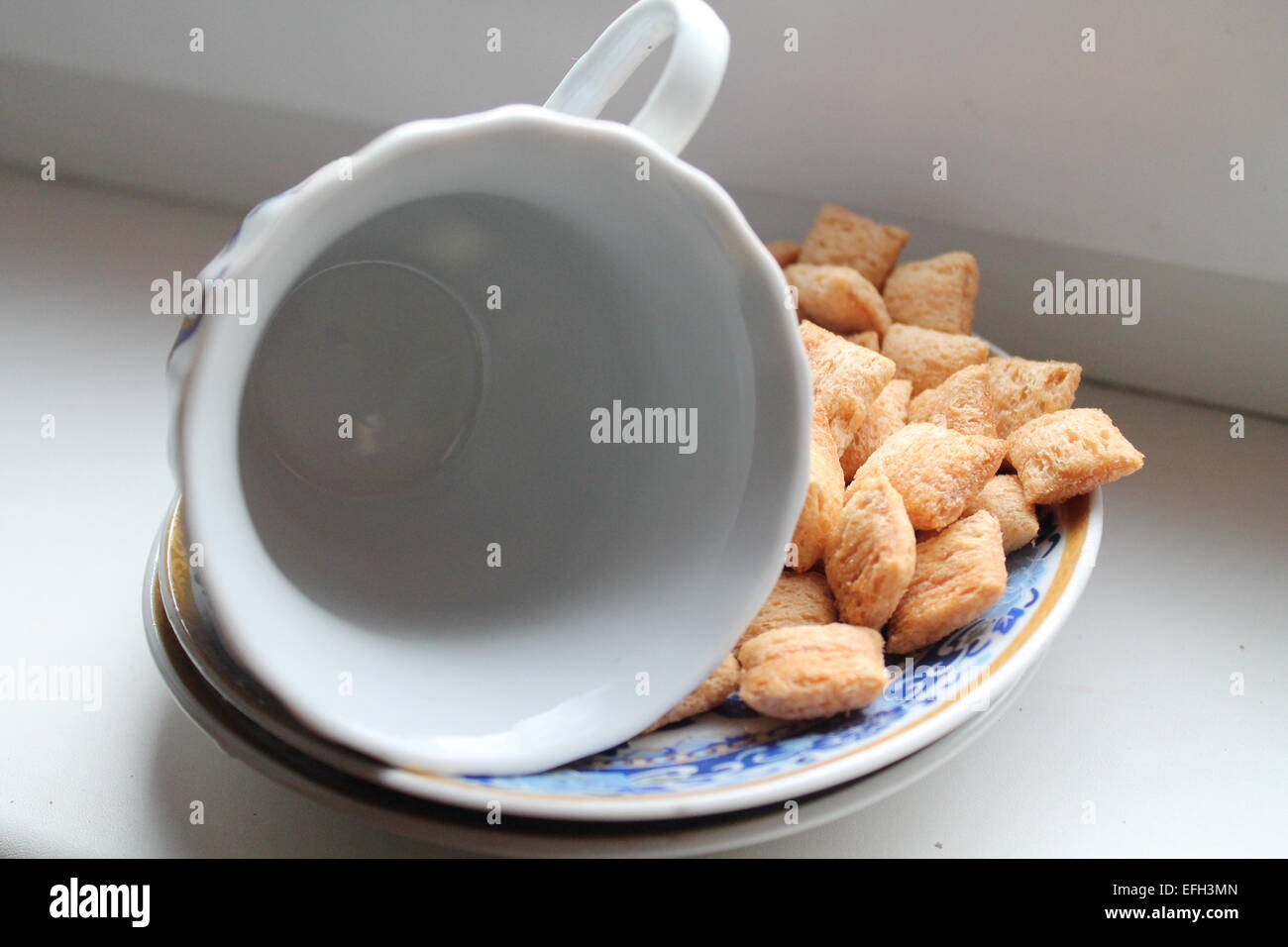 empty deep porcelain cup lay on the one side on the saucer with crust snack Stock Photo