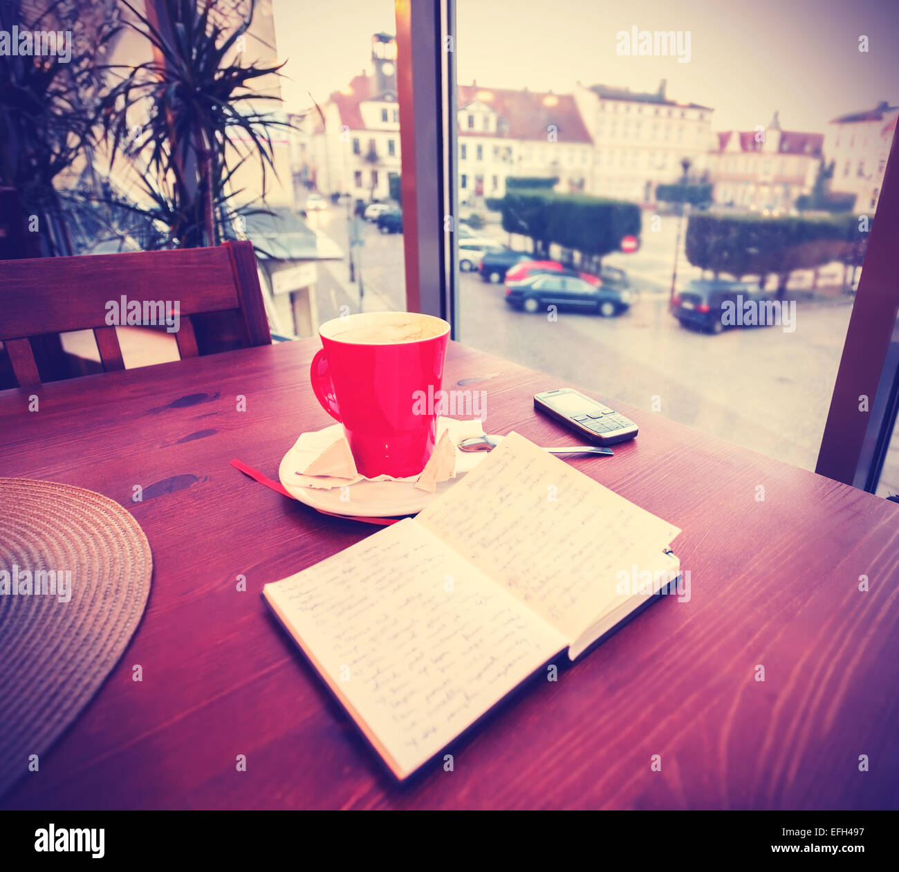 Vintage instagram like toned coffee cup and diary in coffee shop. Stock Photo