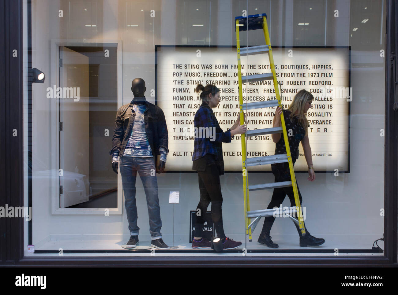 Window dressing designers carry stepladders inside a retailer's shop
