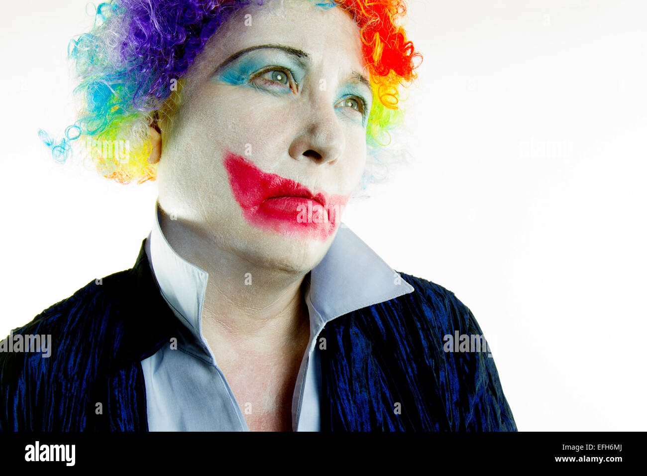 Woman dressed in clown wig and make-up with a sad expression in high tone Stock Photo