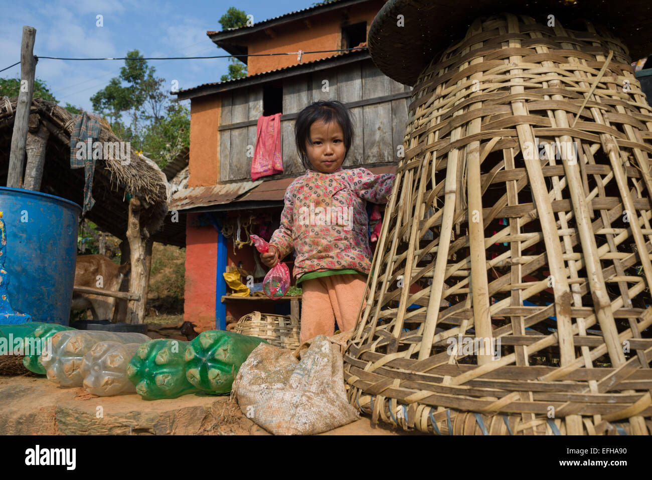 Small child standing next to a basket, in the countryside near Nuwakot, Nepal Stock Photo