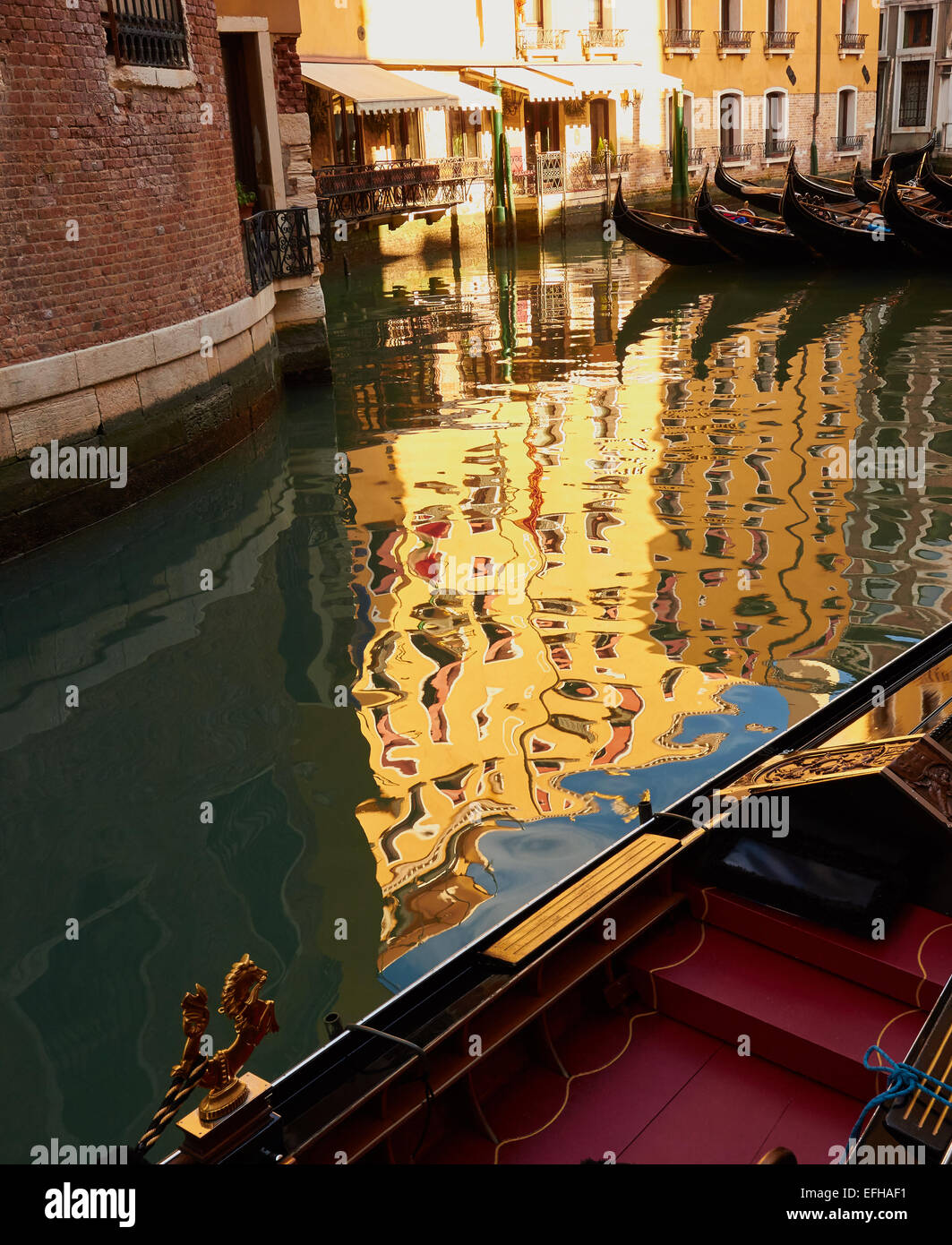 Moored gondolas and reflection of yellow house Venice Veneto Italy Europe Stock Photo