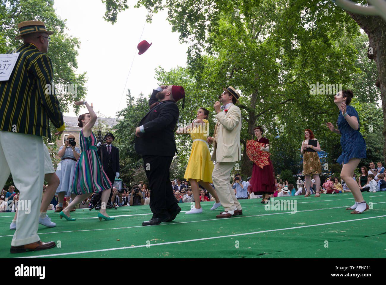 The 10 Anniversary of the Chap Olympiad. A sartorial gathering of chaps and chapesses in Bloomsbury London. Various Chap sports are held at a picnic in the square. Here people compete in Beach Volleybowler: volleyball with a red bowler hat, London, England Stock Photo