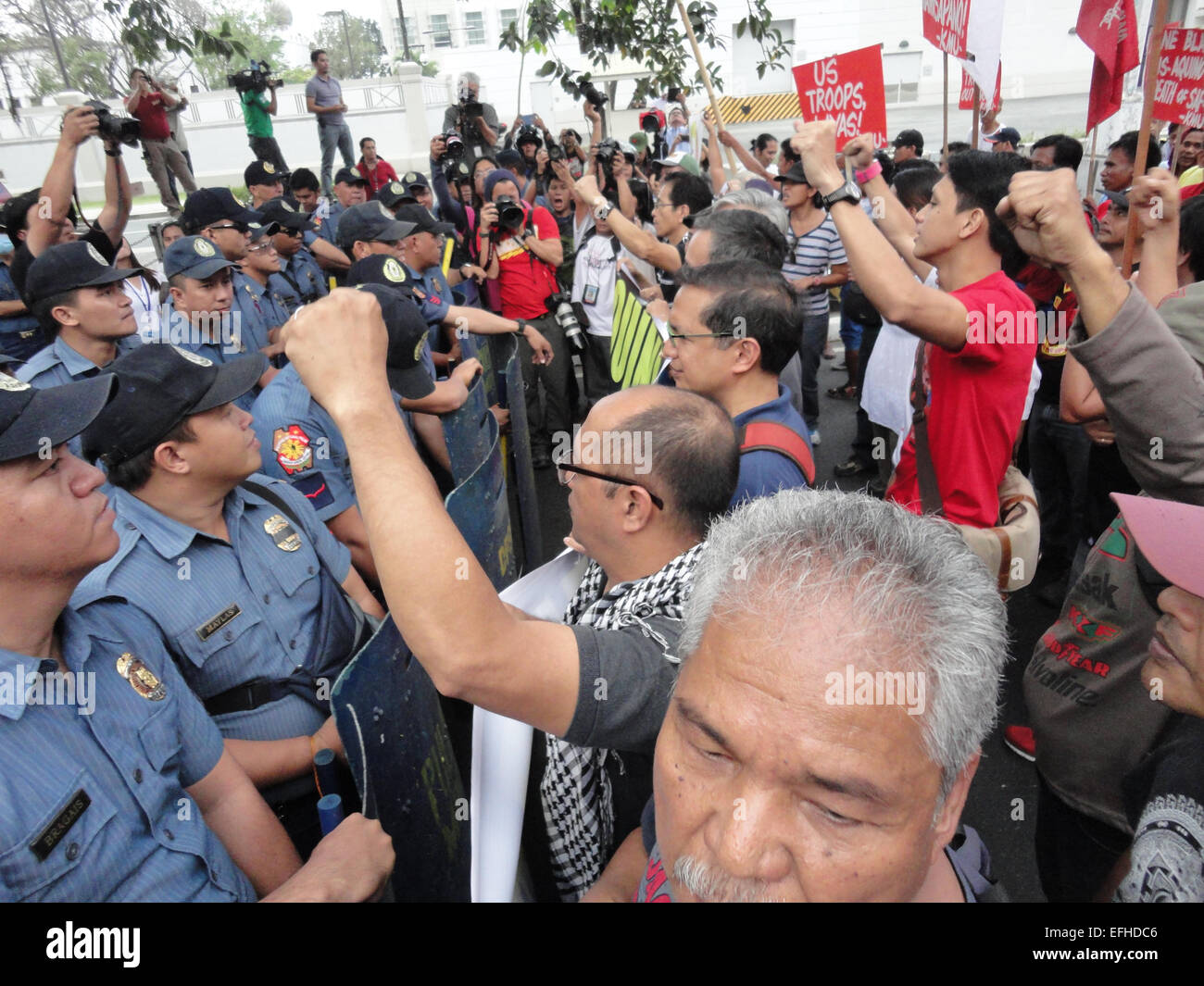 Protesters raise clenched fists as policemen block them from approaching the US Embassy. Protesters accused President Benigno Aquino III, suspended police chief Alan Purisinma, and the US government of being involved in the botched anti-terror operation that killed 44 police commandos, 18 Moro rebels, and 7 civilians. The protest was held on the 116th anniversary of the Filipino-American War that claimed at least 600,000 lives. © Richard James Mendoza/Pacific Press/Alamy Live News Stock Photo