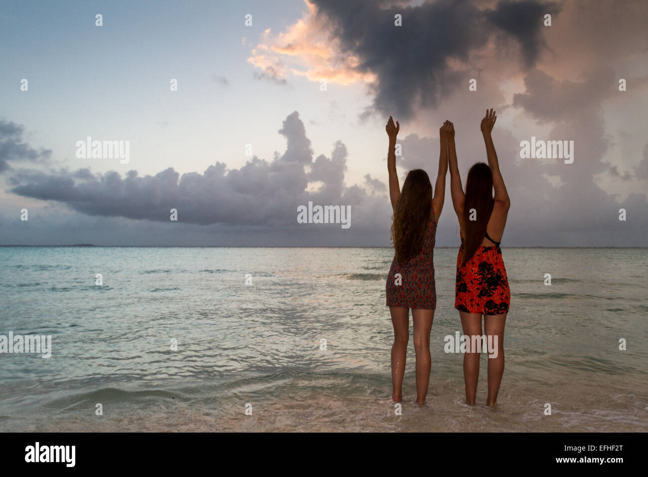 two young women enjoying the sunset at the beach near Cancun in Mexico Stock Photo