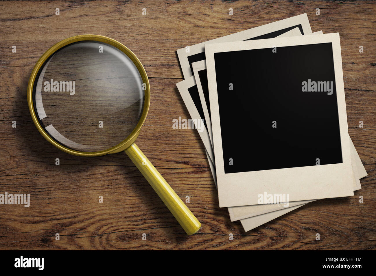 magnifying glass or loupe with old photo frames stack on wood table Stock Photo