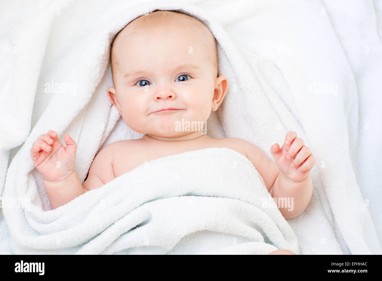 Cute smiling baby girl lying on white towel Stock Photo