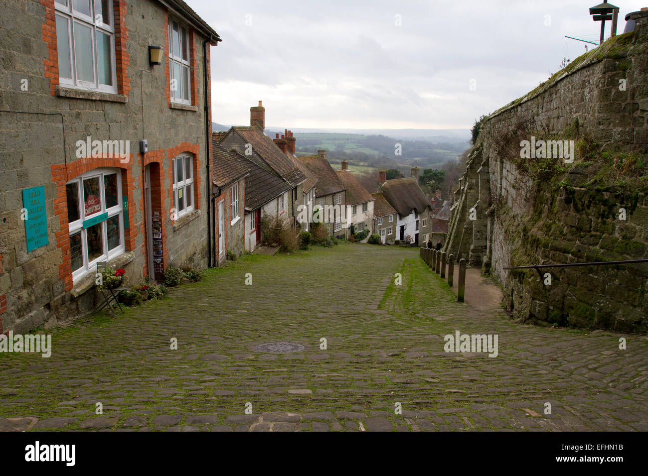 View at the top of Gold Hill, famous cobbled street in Shaftesbury, Dorset, England, looking downhill and to countryside beyond. Stock Photo