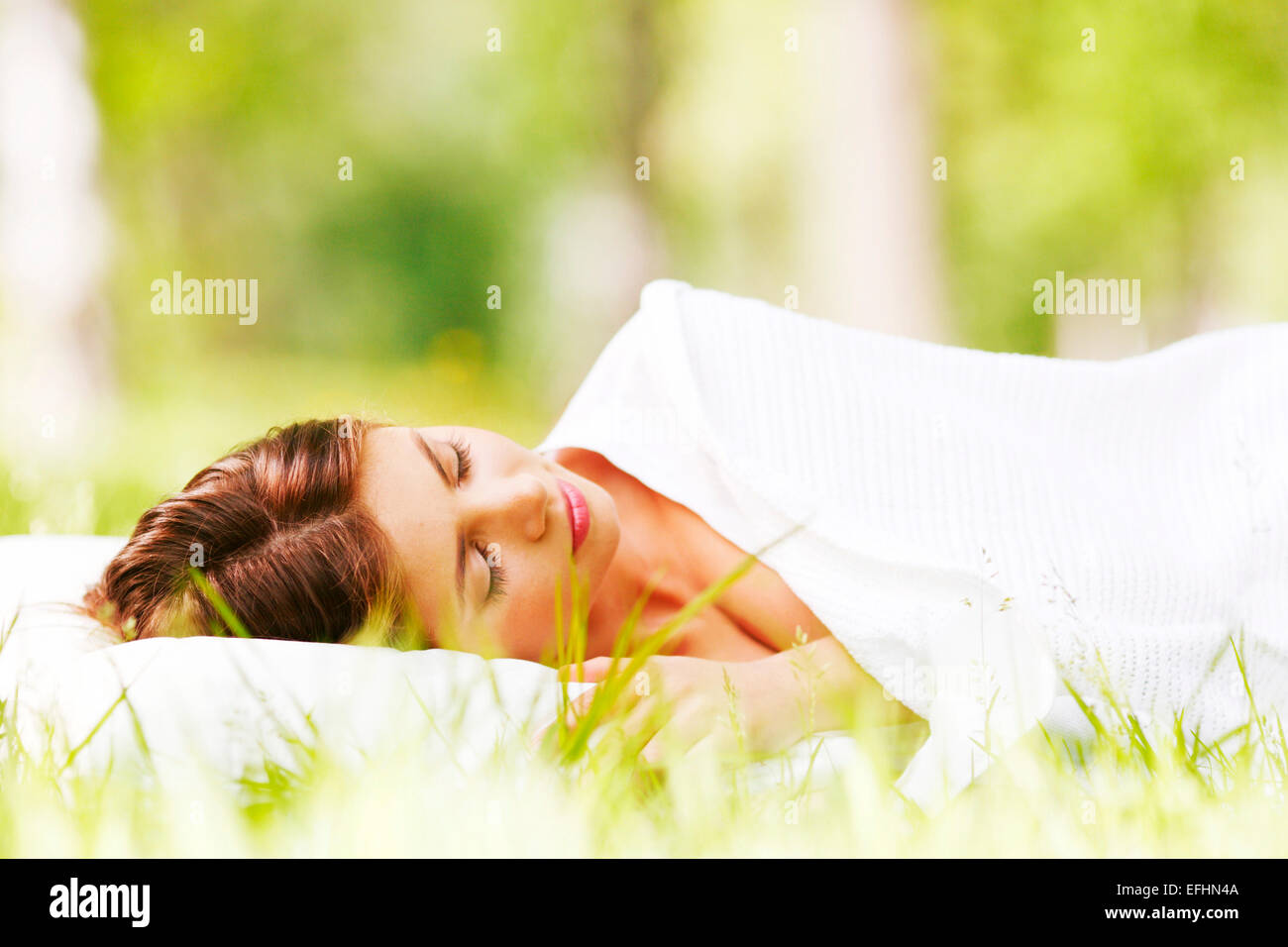 Young woman sleeping on white pillow in fresh spring grass Stock Photo