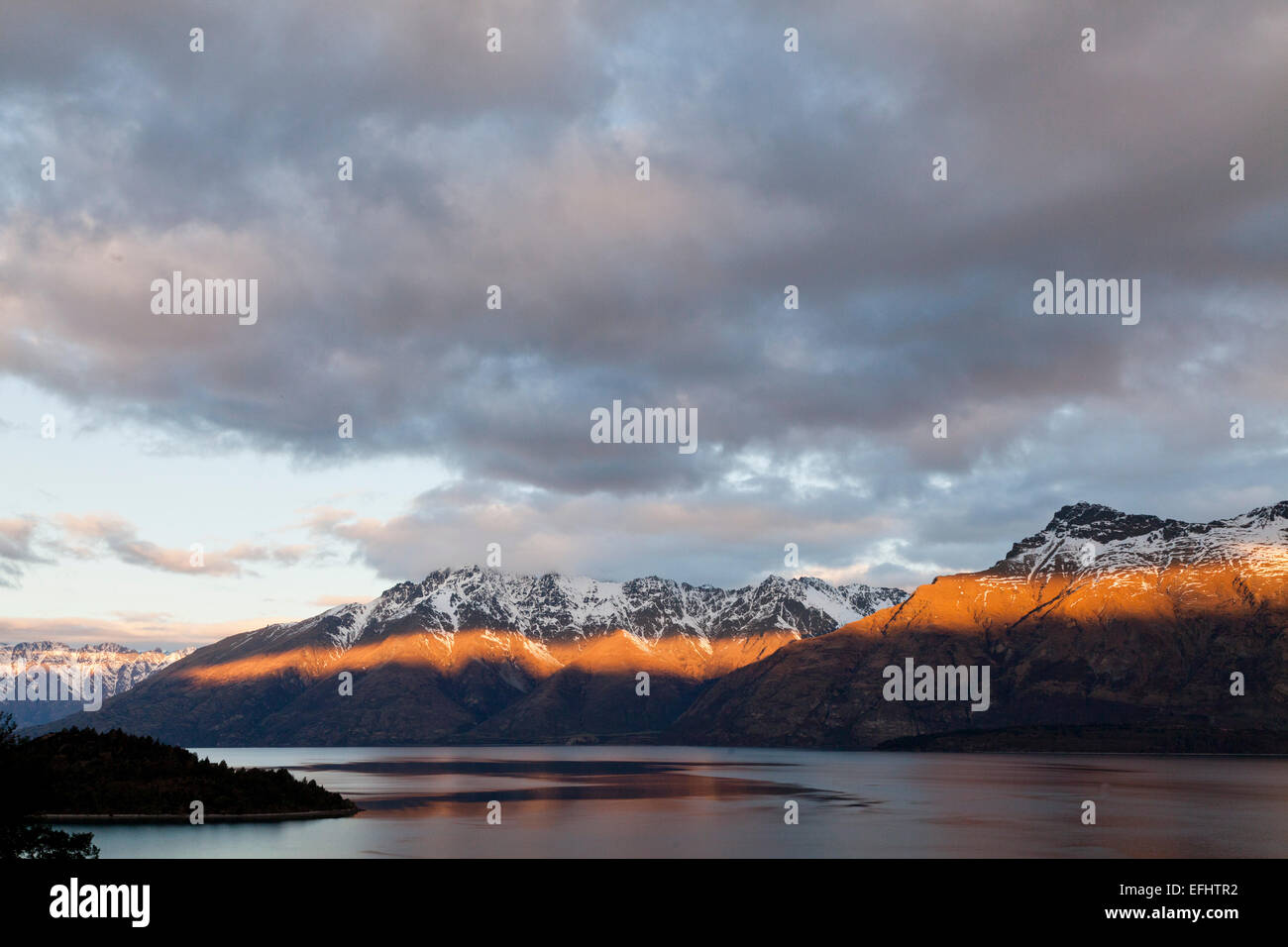 Ray of light from the setting sun on Thomson Mountains, Lake Wakatipu, Queenstown, South Island, New Zealand Stock Photo