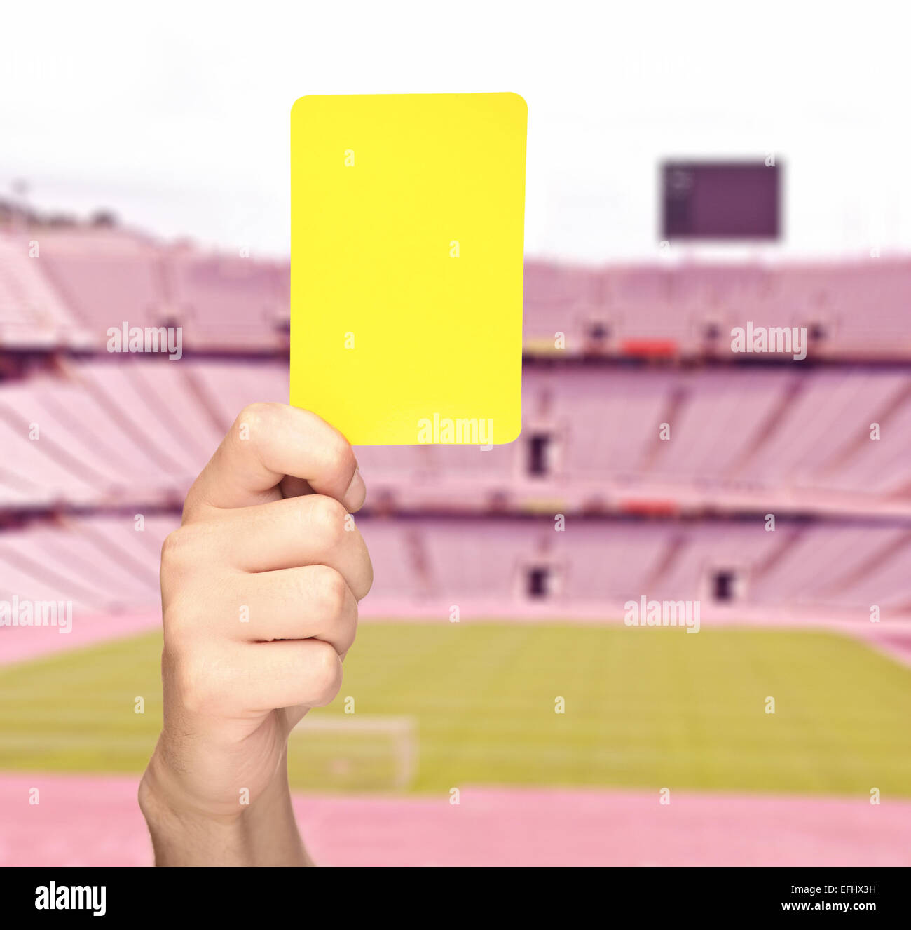 Hand showing a yellow card in front of an empty stadium shot with tilt