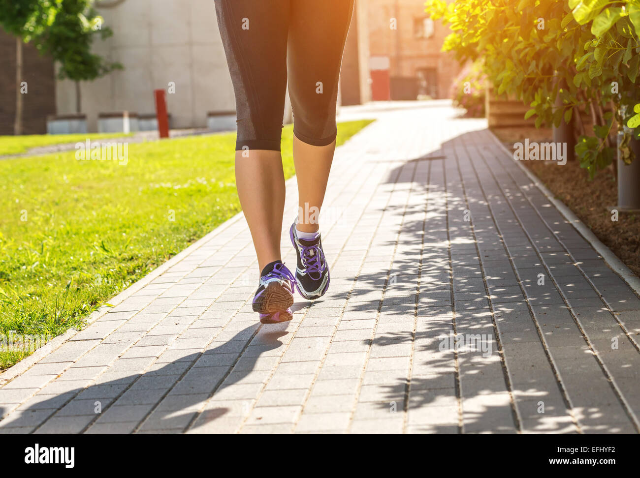 Running woman in black sports outfit (half body photo) on the sidewalk Stock Photo