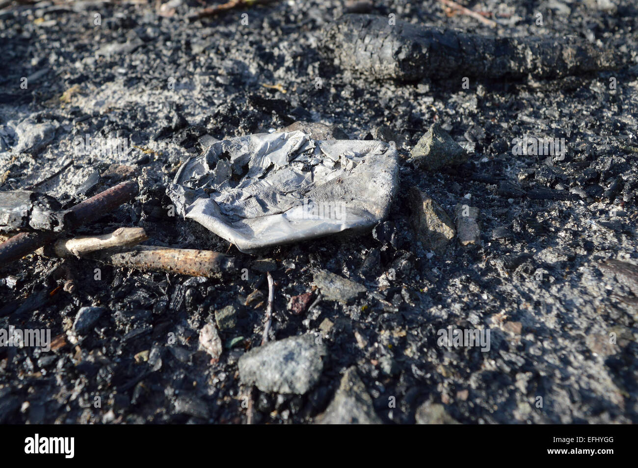 Close up of discarded burnt rubbish left on the floor outdoors. Stock Photo