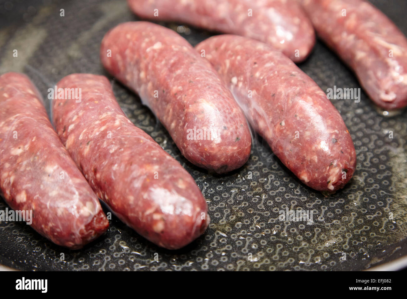 frying low fat venison sausages in a pan with little fat content Stock Photo