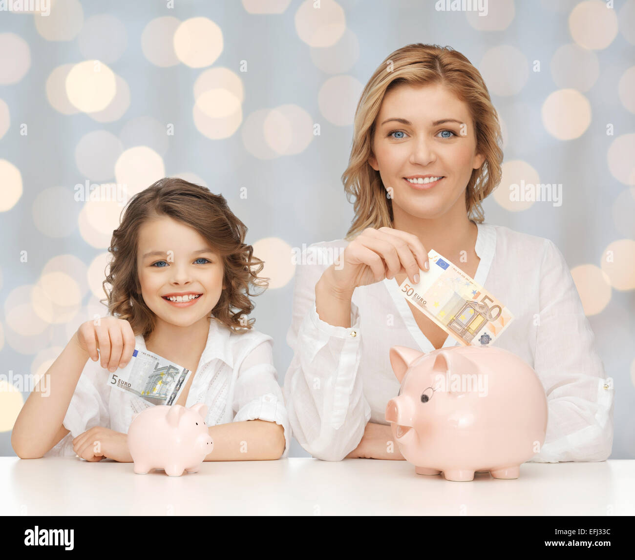 mother and daughter putting money to piggy banks Stock Photo - Alamy