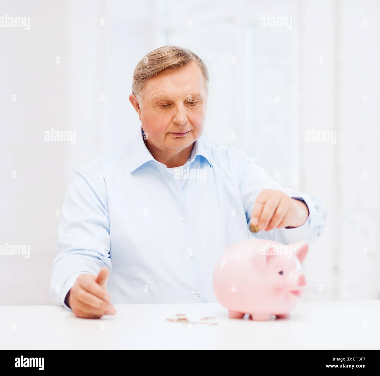 old man putting coin into big piggy bank Stock Photo - Alamy