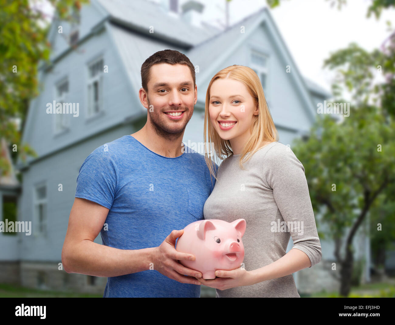 smiling couple holding piggy bank over house Stock Photo - Alamy