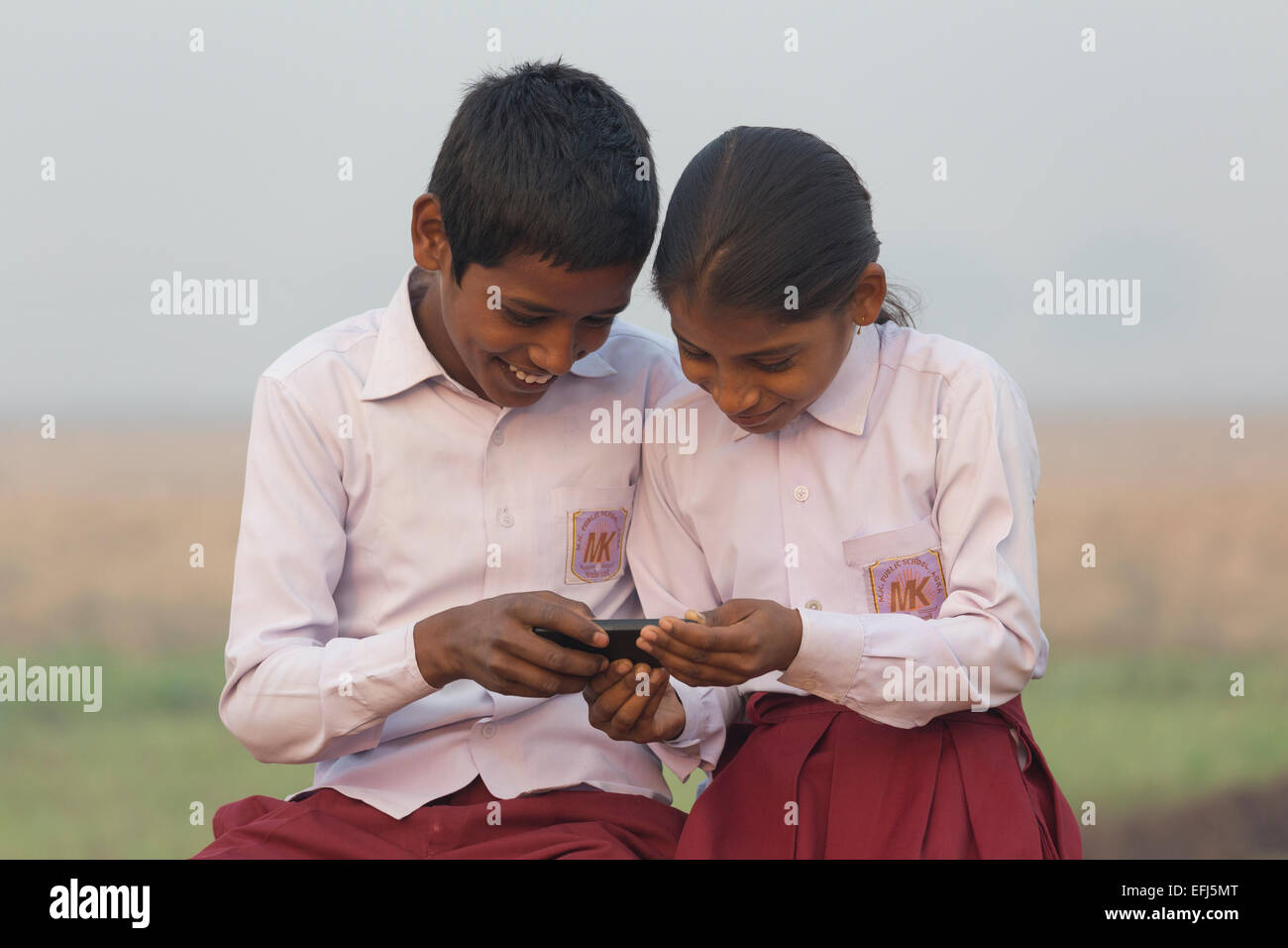 India, Uttar Pradesh, Agra, Indian  village boy and girl  looking at photos on a smartphone Stock Photo