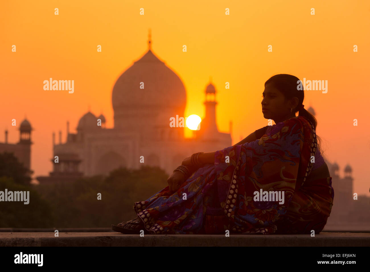 India, Uttar Pradesh, Agra, young Indian woman in contemplative mood at sunset with Taj Mahal in distance Stock Photo