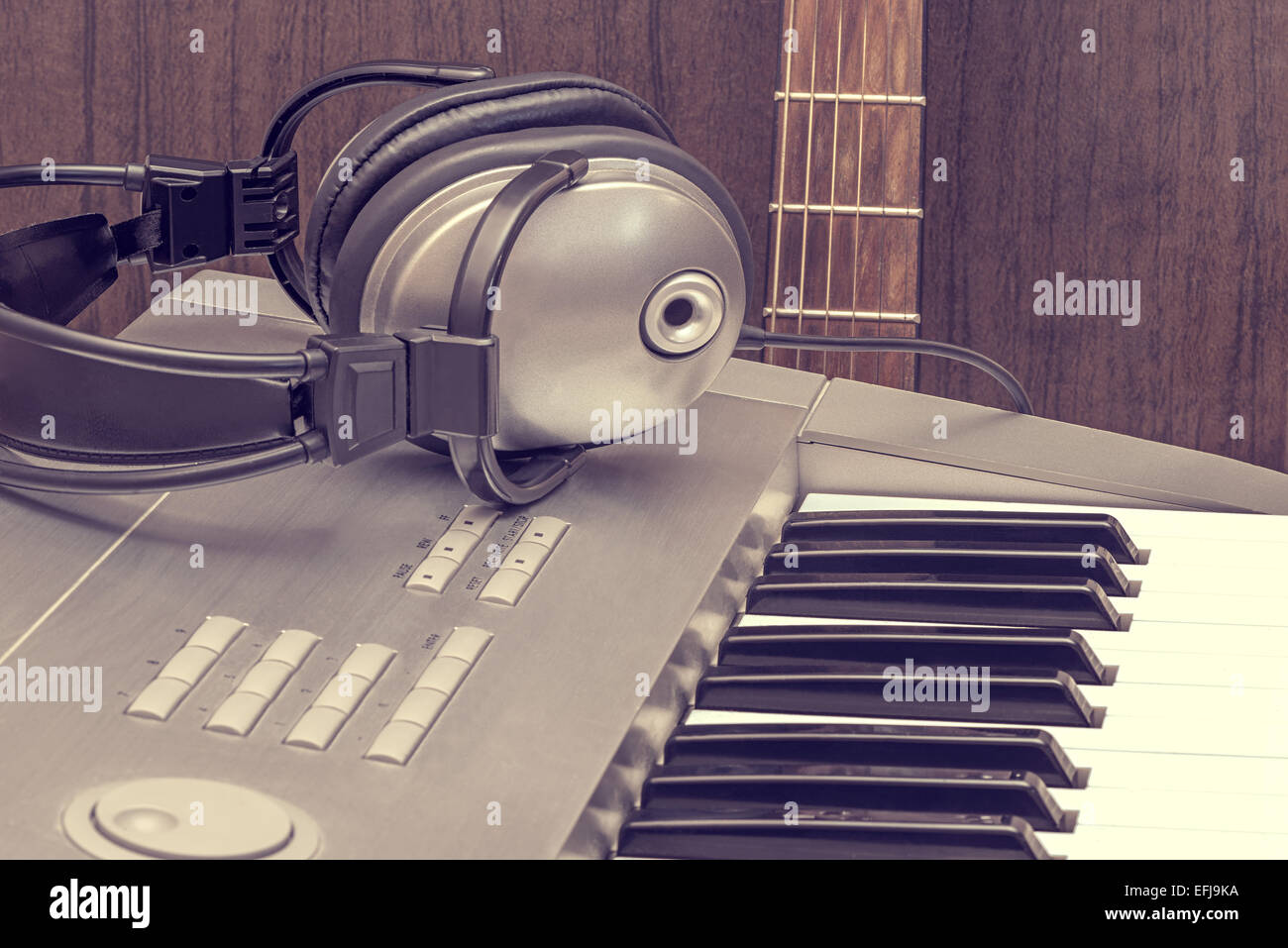 Digital midi keyboard, headphones and acoustic guitar in the studio. Stock Photo