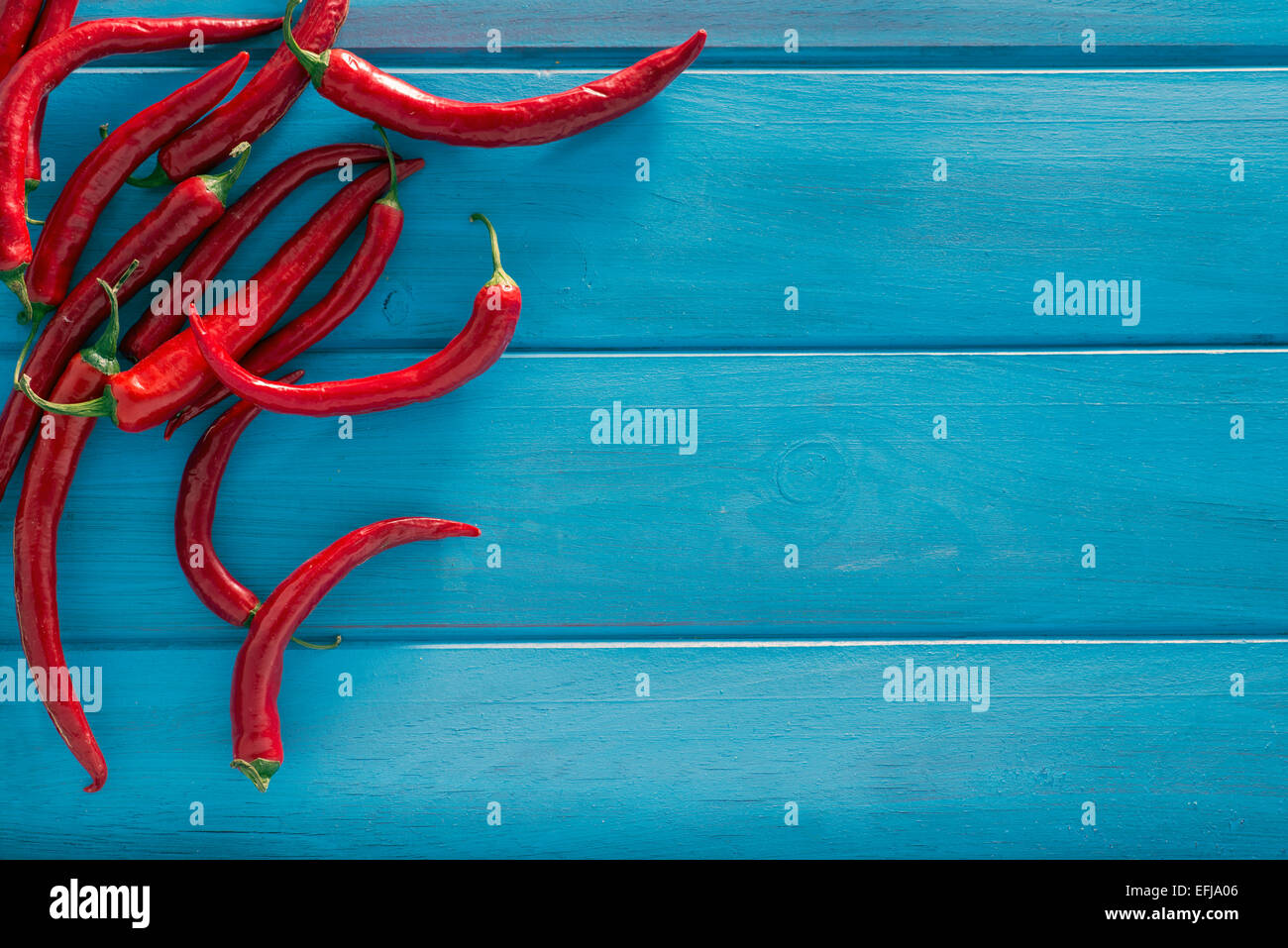 Red peppers on a wooden table painted blue. Space for text Stock Photo