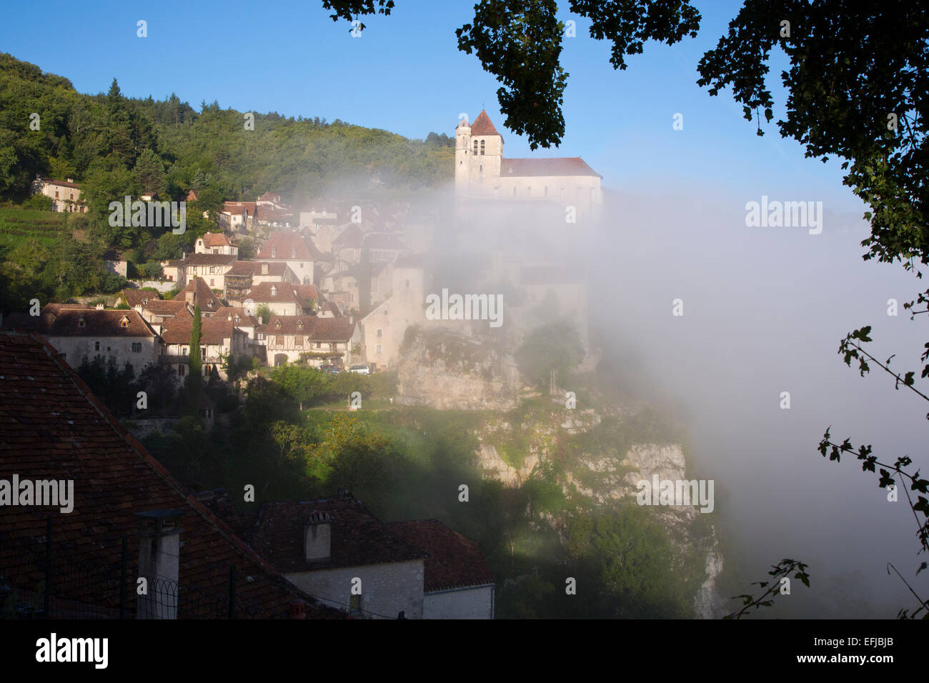 France, Midi-Pyrenees, Lot, Cahors, St Cirq-Lapopie, early morning river mist clears the village on a sunlit September day Stock Photo