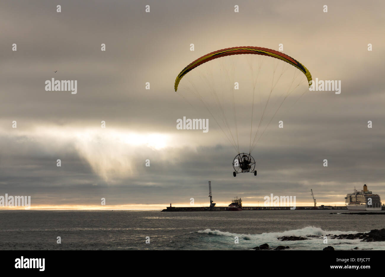 Motorized Paraglider Flight above Ocean Harbor, sunset Stock Photo