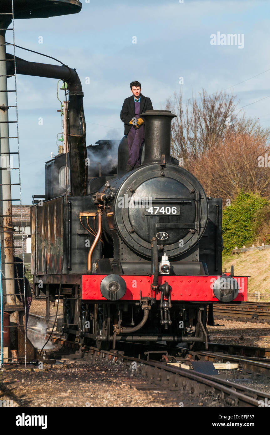 Train driver standing on top of Class 3F 0-6-0T Jinty steam loco taking on water at Loughborough on the Great Central Railway Stock Photo