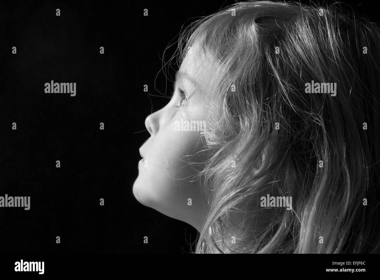 Black and white portrait of a young girl in profile, isolated on black ...