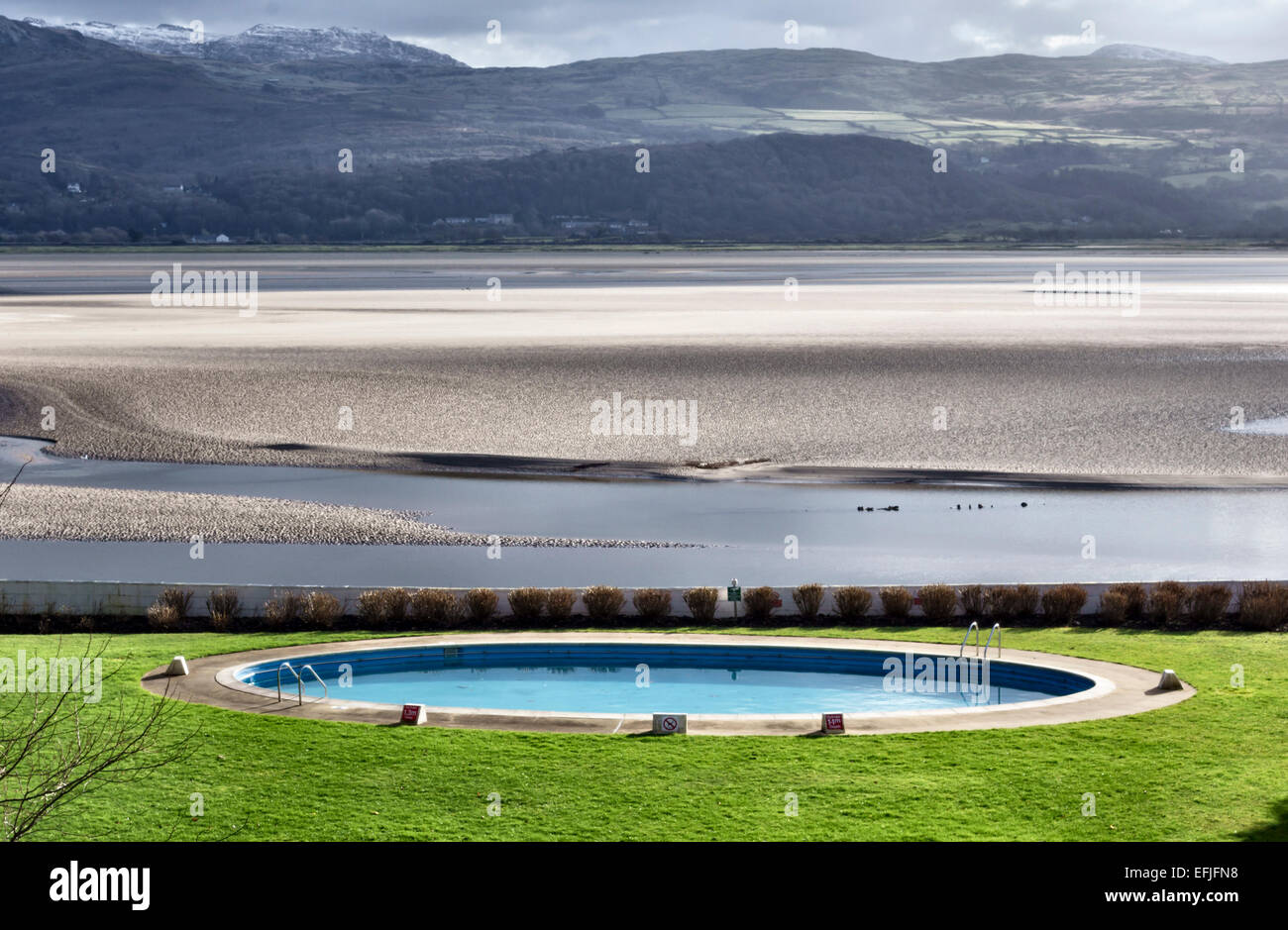 Portmeirion, North Wales, UK. The Portmeirion Hotel circular swimming pool overlooks the sands of the River Dwyryd estuary and the mountains beyond Stock Photo