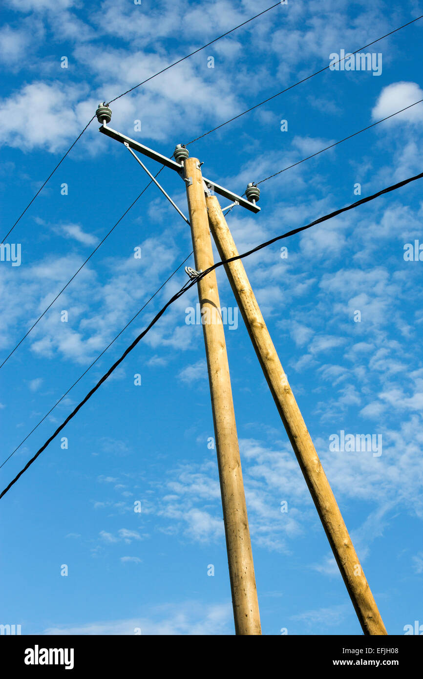 New wooden utility pole with power line wires and support against blue sky , Finland Stock Photo