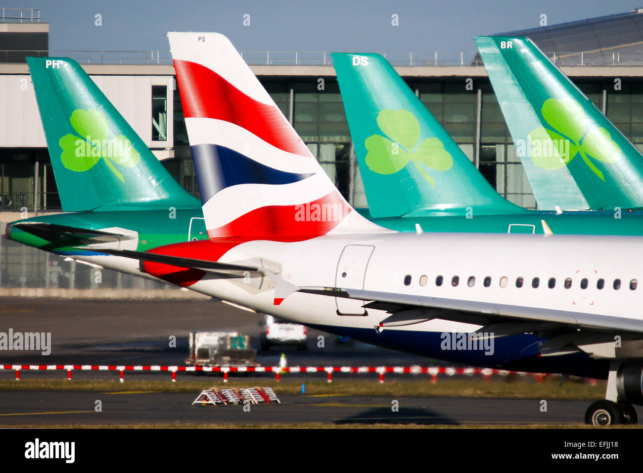 British Airways Airbus A319 taxis past a trio of Aer Lingus aircraft, as speculation mounts of their impending takeover by IAG. Stock Photo