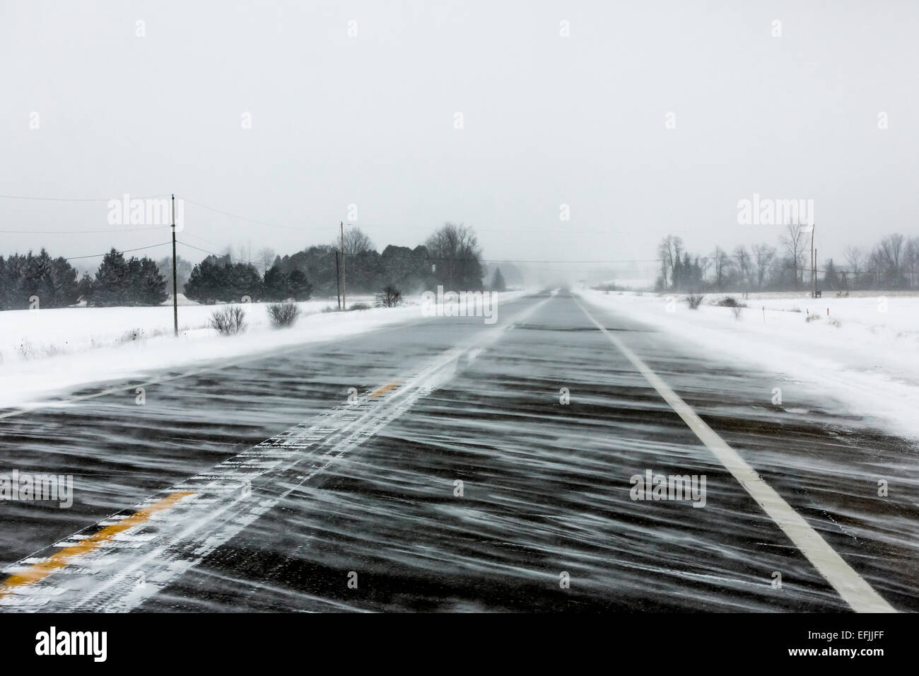 Blowing snow during a cold & windy day along M-20 between Remus and Mt. Pleasant in the rural landscape of central Michigan, USA Stock Photo