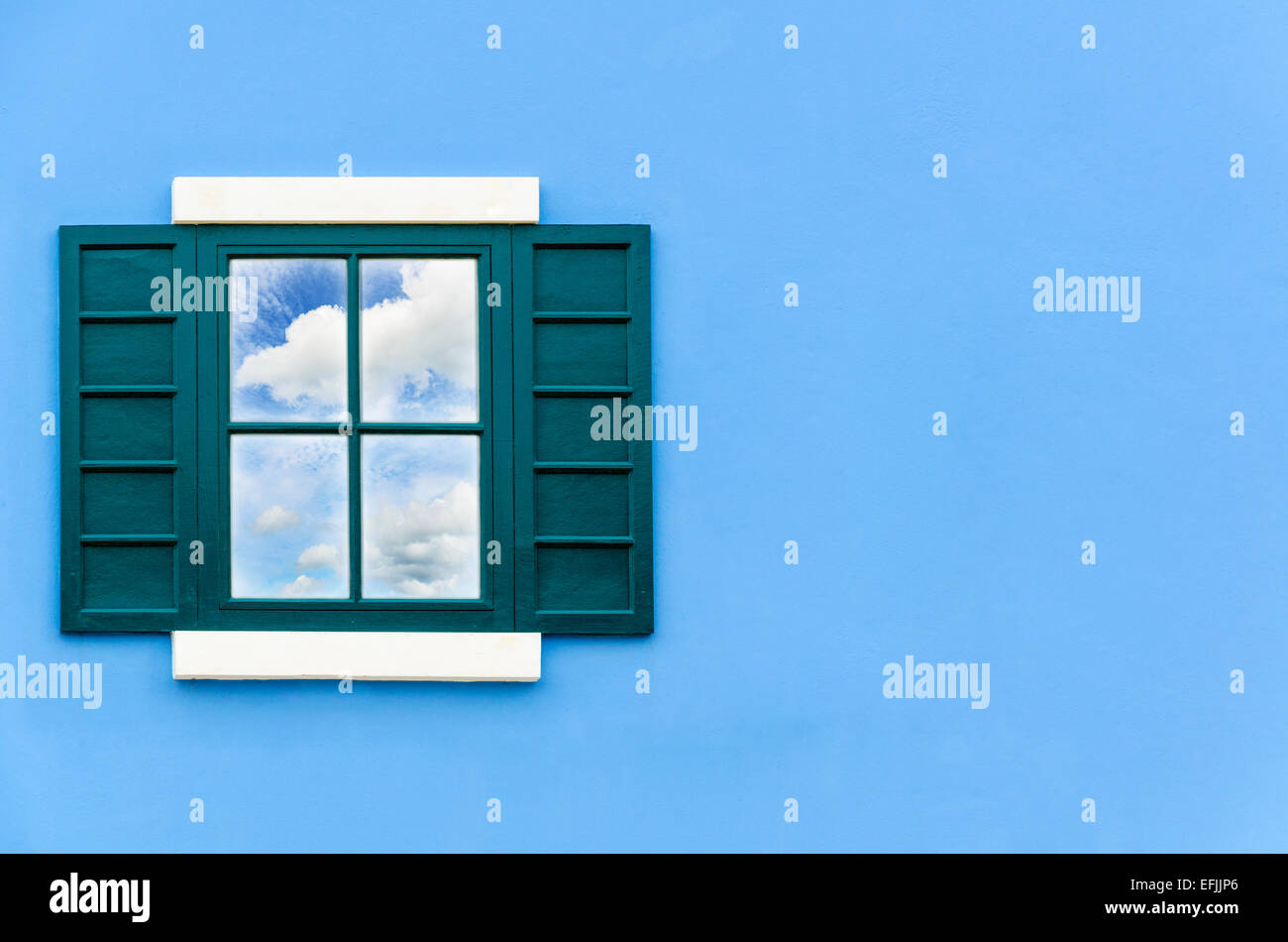 Sky and cloud reflection in green window glass on blue wall of house, Italy retro style Stock Photo