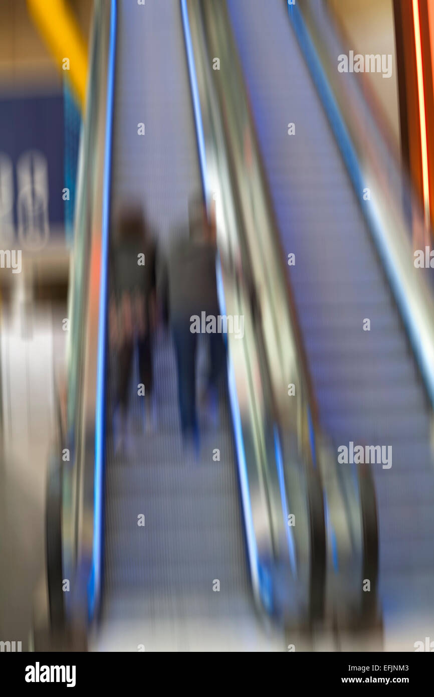 abstract blur of couple going up escalator in The O2 arena at Peninsula Square, London UK in February Stock Photo