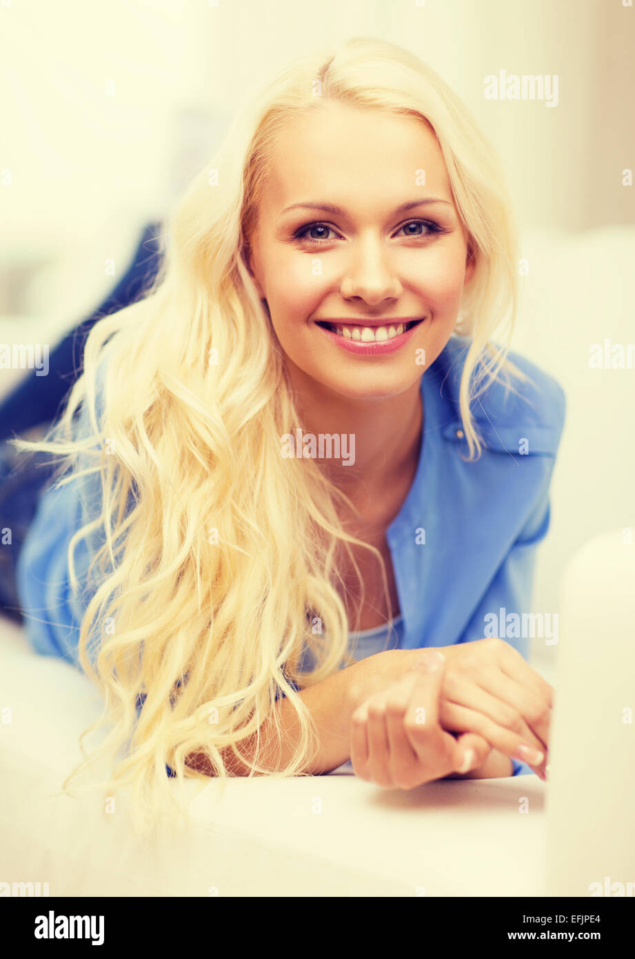 smiling young woman lying on sofa at home Stock Photo - Alamy