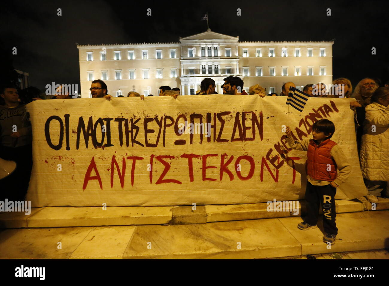 Athens, Greece. 5th Feb, 2015. Protesters stand with a banner outside the Greek Parliament. Thousands of Greeks assembled at Syntagma Square, to protest against the fiscal extortion by the Troika, who wants Greece to follow their instruction in return for providing needed money to the Greek banks. Credit:  Michael Debets/Pacific Press/Alamy Live News Stock Photo