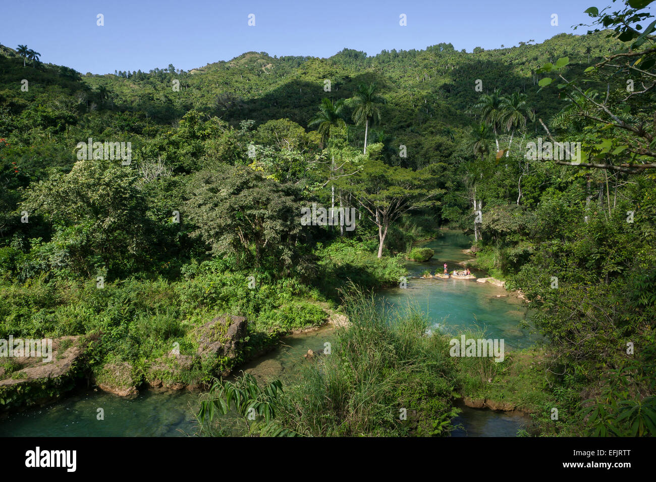 Cubans picnicking on large rocks next to clear water pools downstream of the El Nicho waterfall, Escambray Mountains, Cuba. Stock Photo